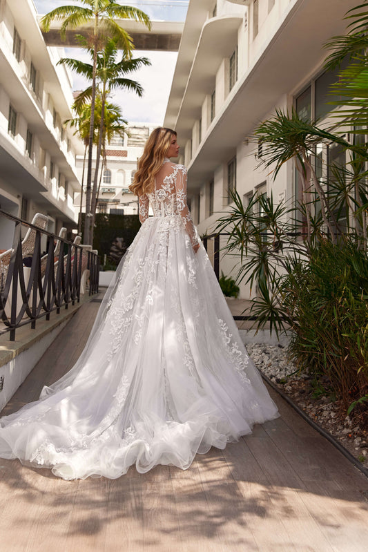 Model showcasing a stunning long sleeve bolero wedding dress with intricate lace details and a flowing train.
