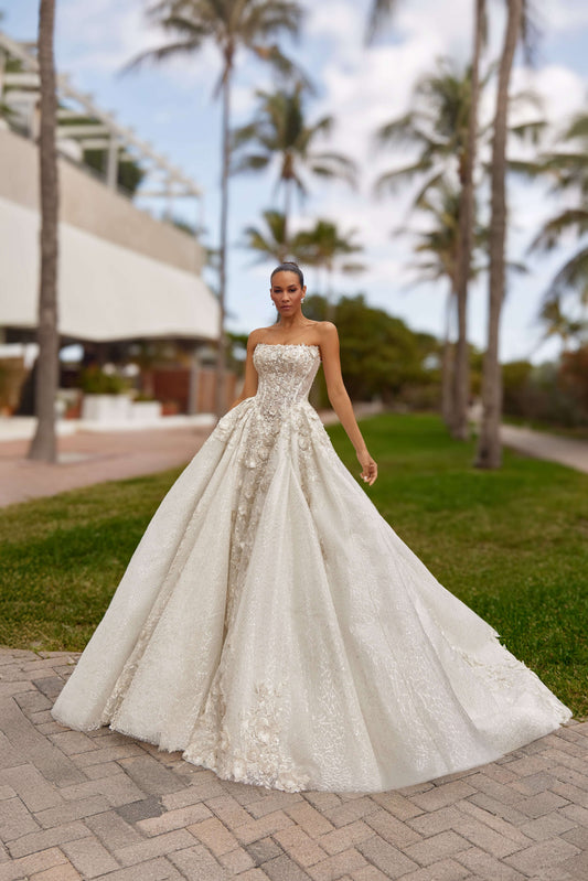 Royal dress with cape in a stunning outdoor setting, featuring elegant embellishments and a flowing silhouette.