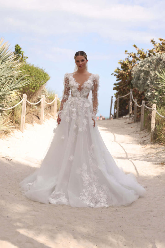 Romantic A-line dress with puff sleeves displayed on a model walking down a sandy path surrounded by greenery.