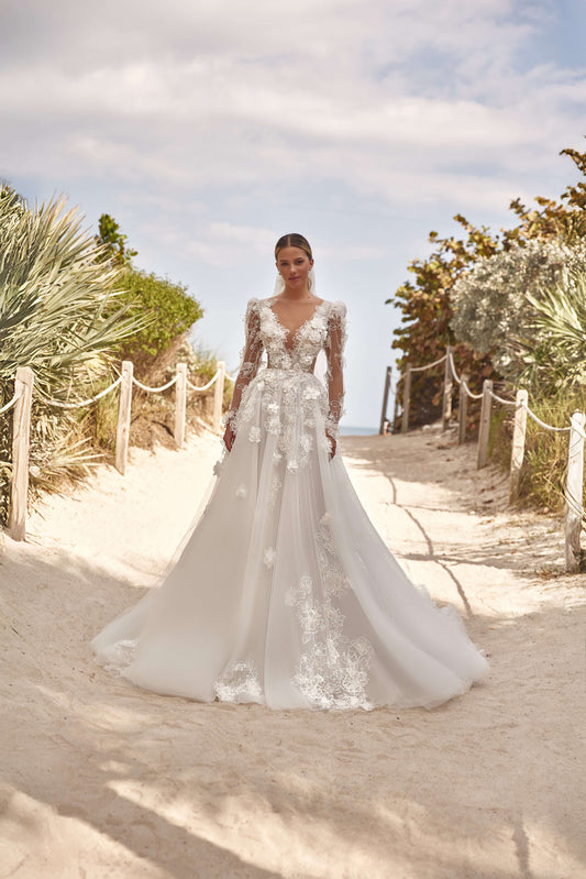 Romantic A-line dress with puff sleeves worn by a woman walking on a sandy path surrounded by greenery.