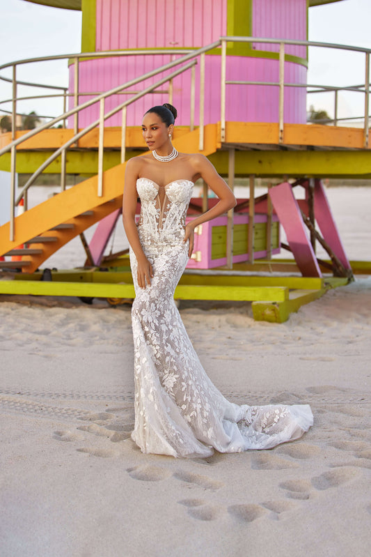 Elegant fitted dress with lining on a model at the beach in front of a colorful lifeguard tower.