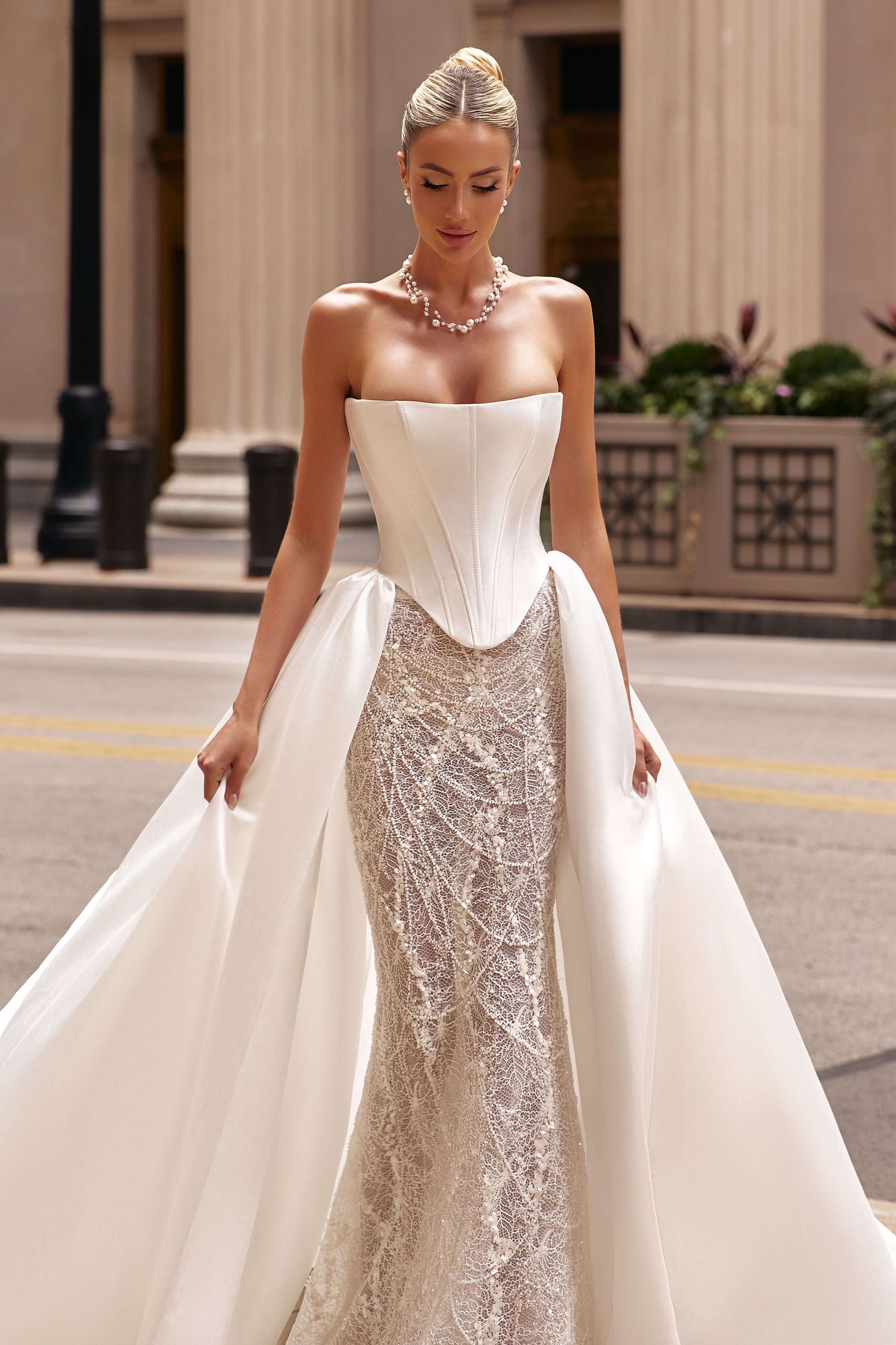 Elegant model wearing a shantung satin corset dress with an attached train and intricate beading, captured on the streets.
