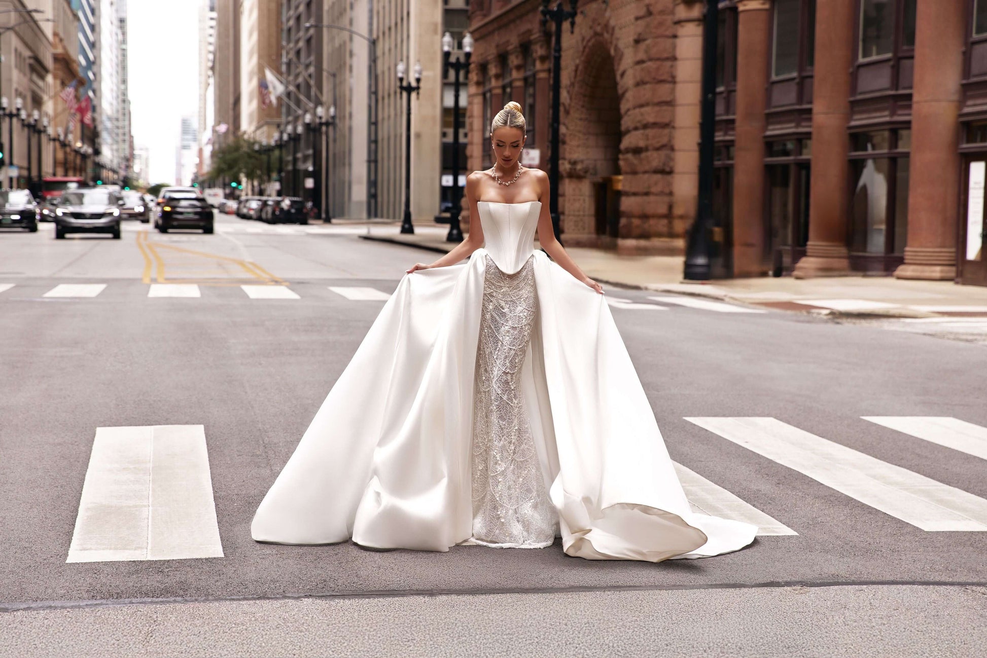 Elegant woman wearing a shantung satin corset dress with a train, posing in the middle of a city street.