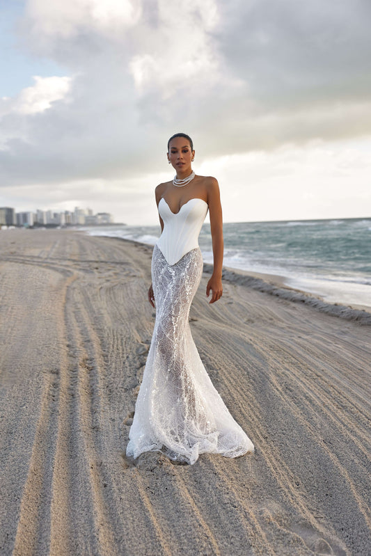Modern corset skirt set showcased by a model on the beach, featuring a fitted bodice and flowing lace skirt.