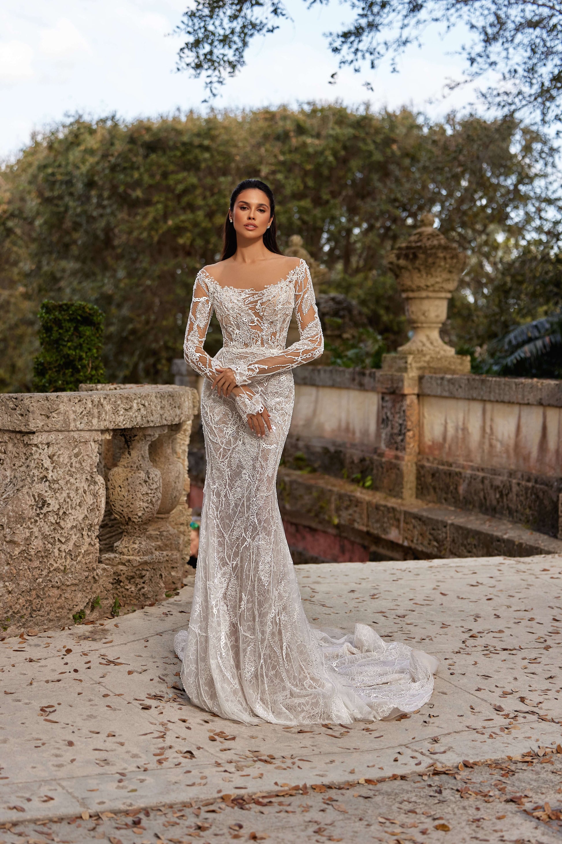 textured wedding dress with lining featuring long sleeves and a fitted silhouette in an outdoor setting