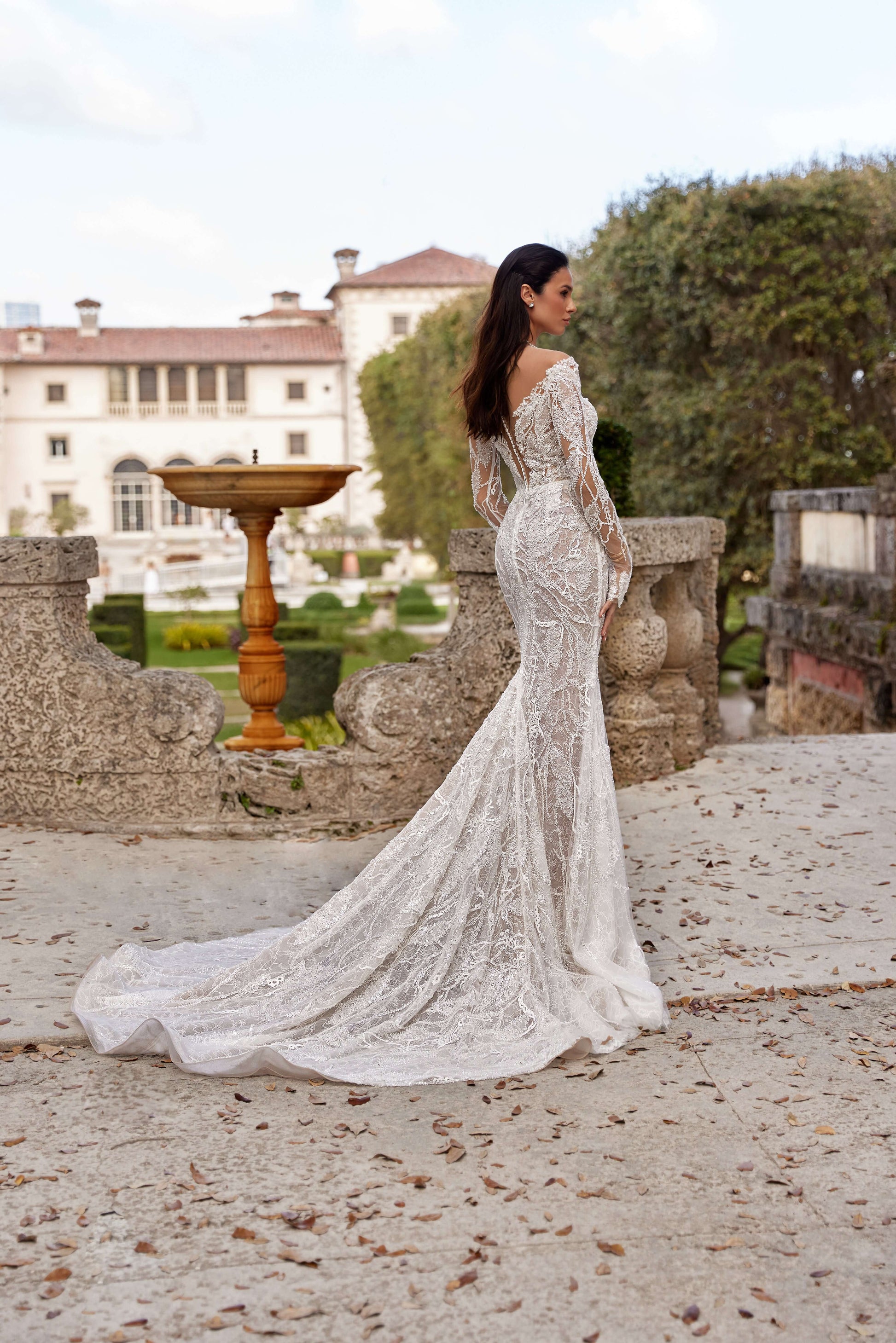 Textured wedding dress with lining, showcasing a fitted silhouette, seen from the back in a charming outdoor setting.