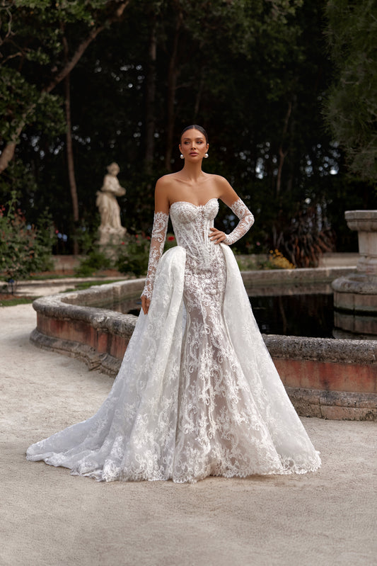 Bella wedding dress with detachable train showcased in a scenic outdoor setting, highlighting its elegant design and intricate lace.