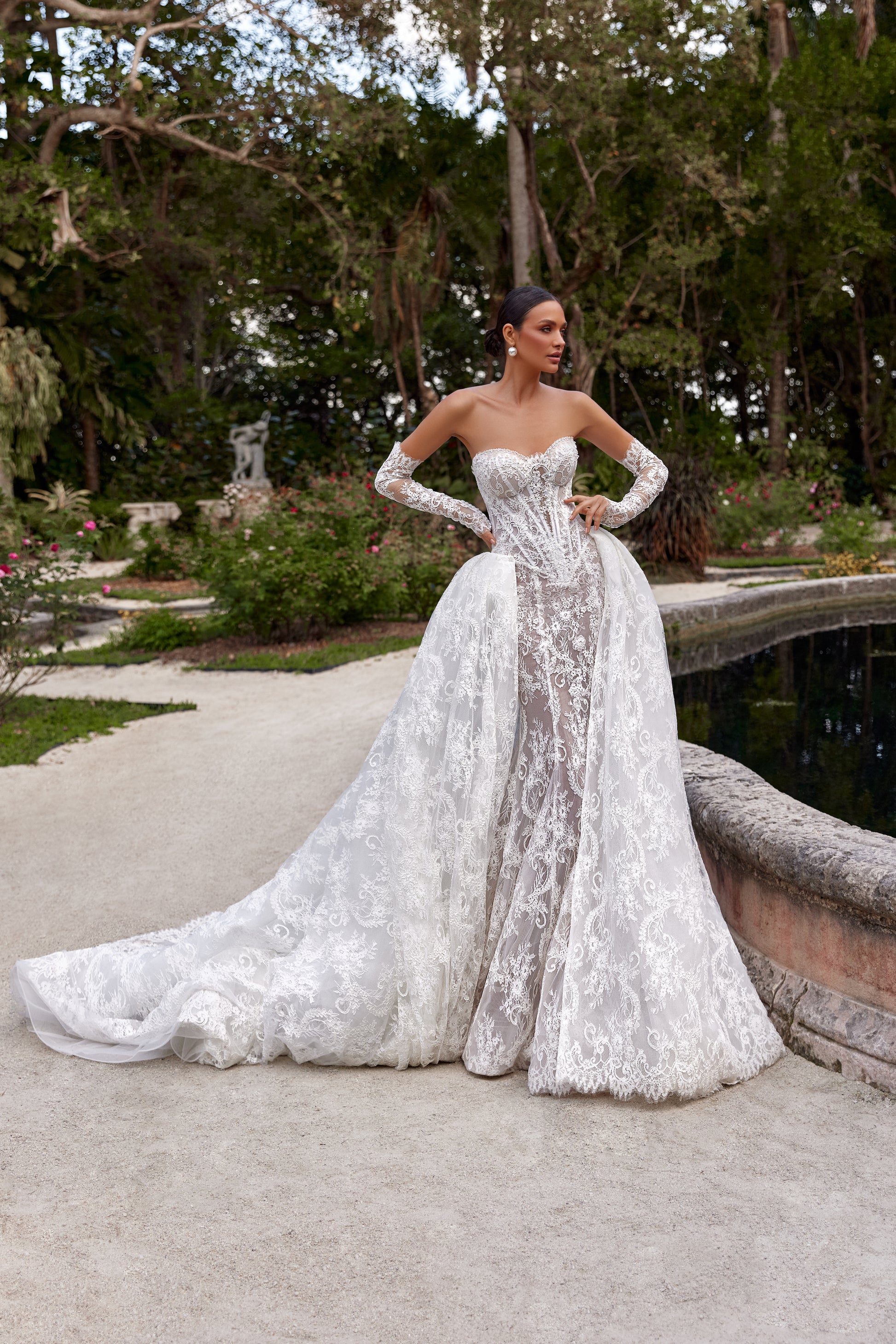 Bella wedding dress with detachable train showcased in a picturesque garden setting.