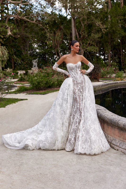 Bella wedding dress with detachable train showcased in a picturesque garden setting.