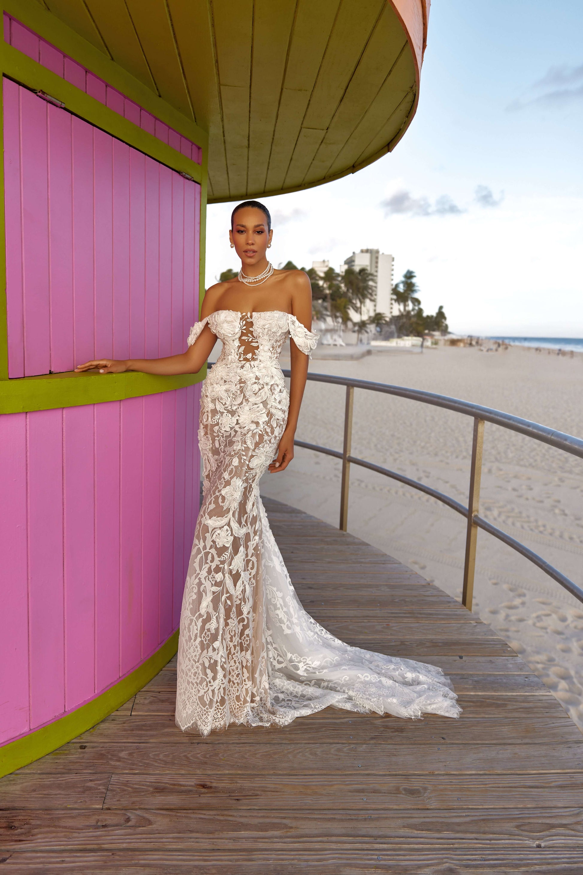 Chloe lined dress on display by a beachside setting with a colorful pink hut, showcasing elegance and style.