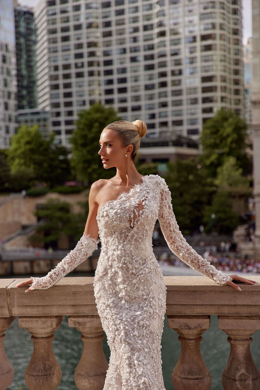 Alegra asymmetrical neckline mermaid dress with intricate detailing, model posing against a city skyline.
