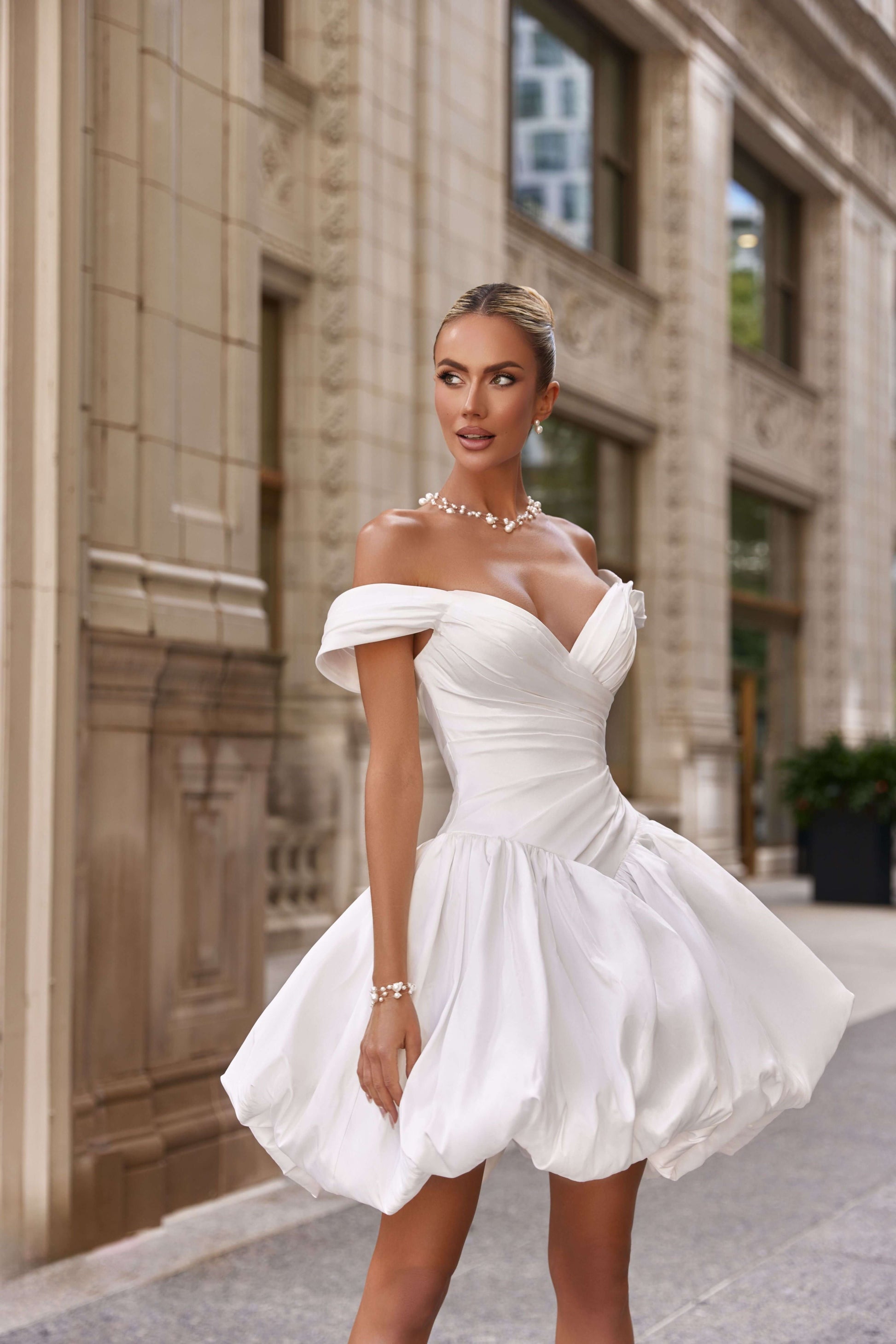 Model wearing a stunning white mini corset dress with off-the-shoulder sleeves, perfect for making a statement.